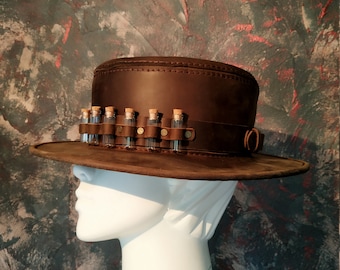 May include: A brown leather hat with a wide brim and a band of small glass vials around the crown.