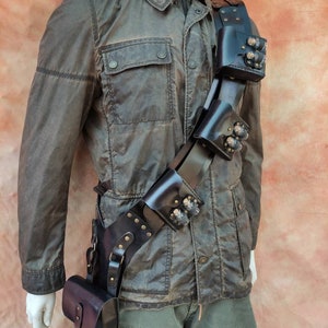 May include: A black leather belt with multiple pouches and metal accents. The belt is worn diagonally across the body and has a small pouch hanging from the bottom.