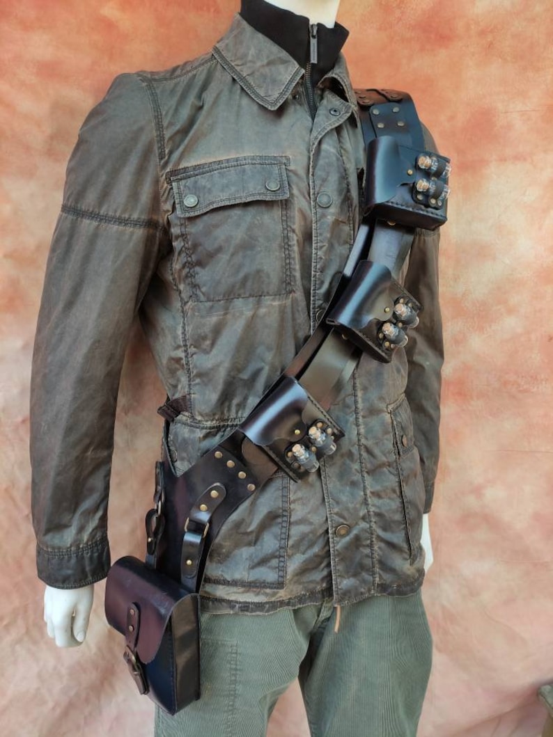 May include: A black leather belt with multiple pouches and metal accents. The belt is worn diagonally across the body and has a small pouch hanging from the bottom.