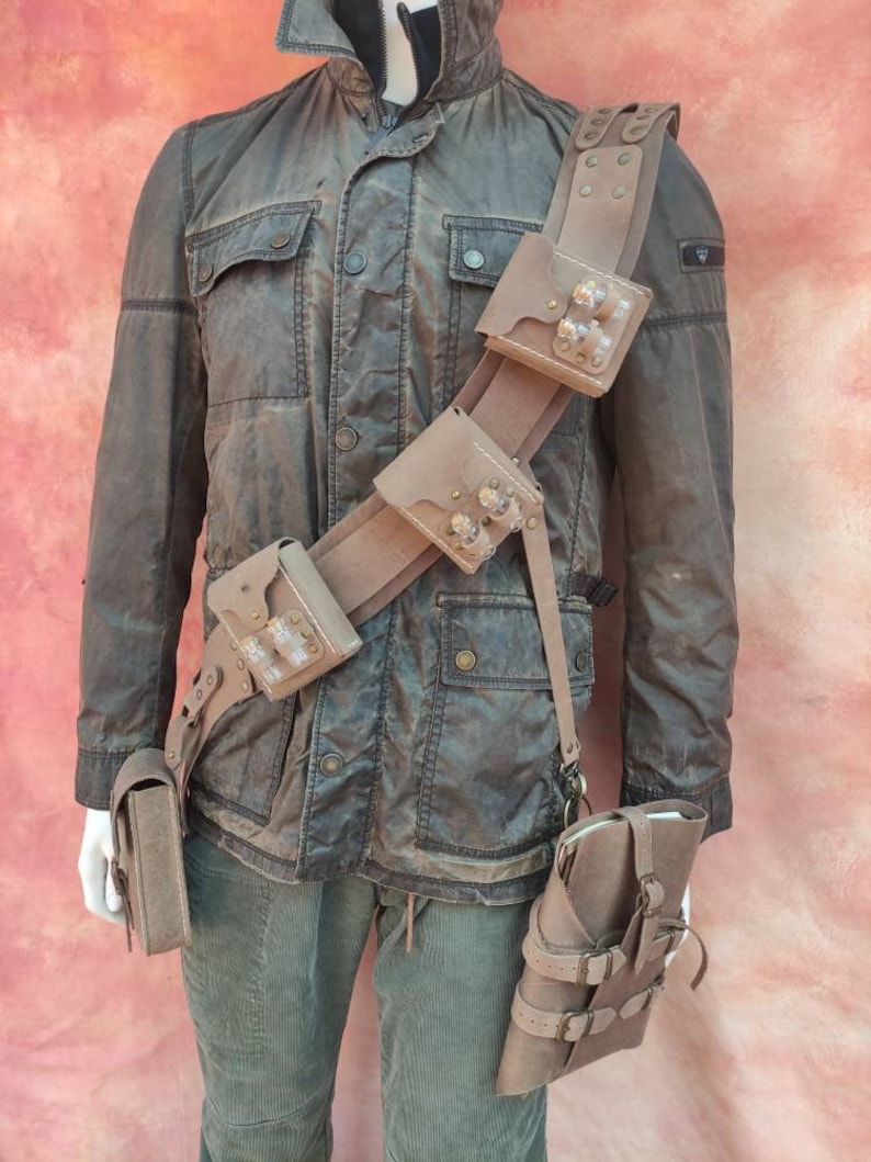 May include: A brown leather belt with multiple pouches and straps. The belt has a buckle and is worn over a brown jacket.