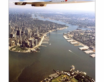 May include: A British Airways Concorde supersonic jet flies over a cityscape with a river and bridges. The aircraft is white with red and blue accents. The city features tall buildings and green spaces.