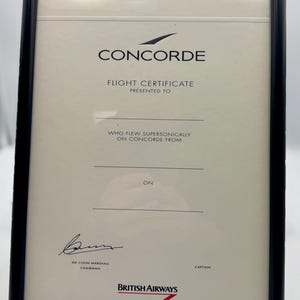 Könnte beinhalten: Ein schwarzer gerahmtes Zertifikat mit dem Text "CONCORDE FLIGHT CERTIFICATE" und "BRITISH AIRWAYS" in Rot und Weiß. Das Zertifikat wird an jemanden verliehen, der mit Concorde Überschallgeschwindigkeit geflogen ist.
