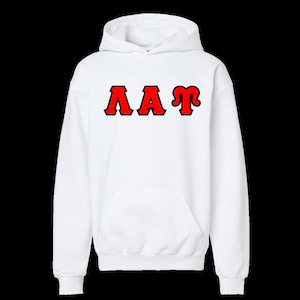May include: A white long-sleeve hooded sweatshirt featuring a front kangaroo pocket and the Greek letters Lambda, Alpha, and Tau printed in red with a black outline across the center of the chest area, creating a bold and clear visual contrast.