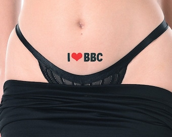 May include: Black thong underwear with a lace front panel. The text "I ❤️ BBC" is printed in black with a red heart. A black mini skirt is visible below the underwear.