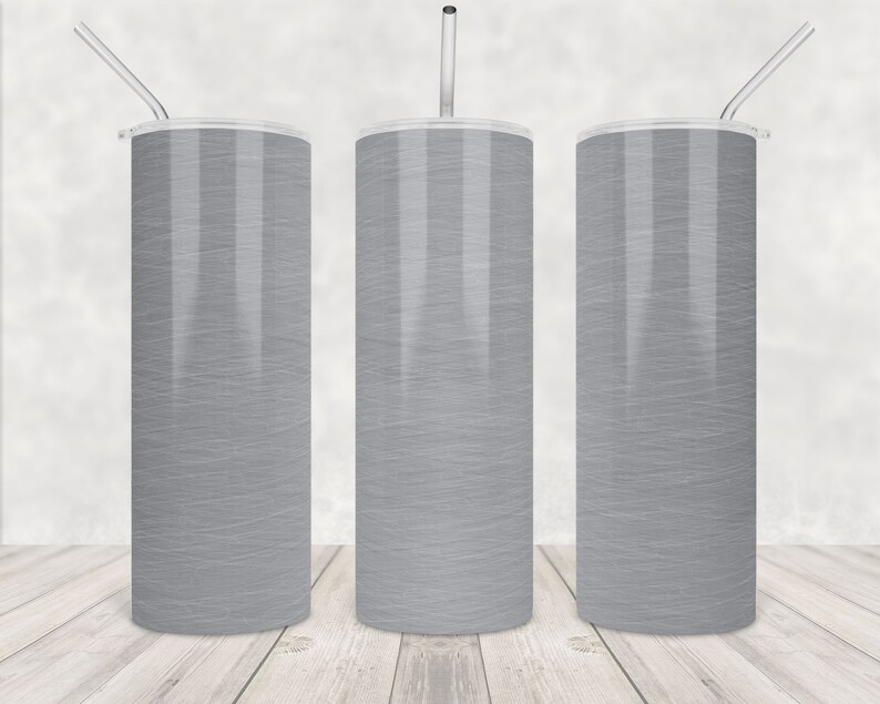 May include: Three tall, cylindrical tumblers with a light grey, textured design. Each tumbler has a clear lid and a silver-coloured straw. The tumblers are displayed on a light wood surface.