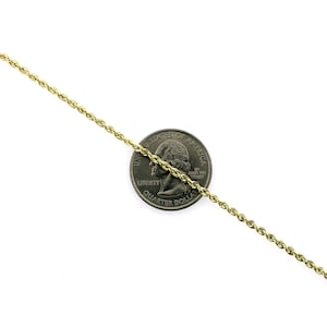 May include: A gold rope chain necklace, shown next to a US quarter for size comparison. The chain is made of a braided, twisted design.