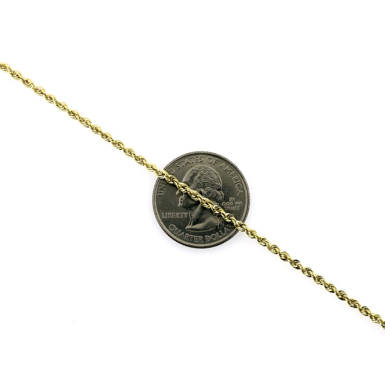 May include: A gold rope chain necklace, shown next to a US quarter for size comparison. The chain is made of a braided, twisted design.