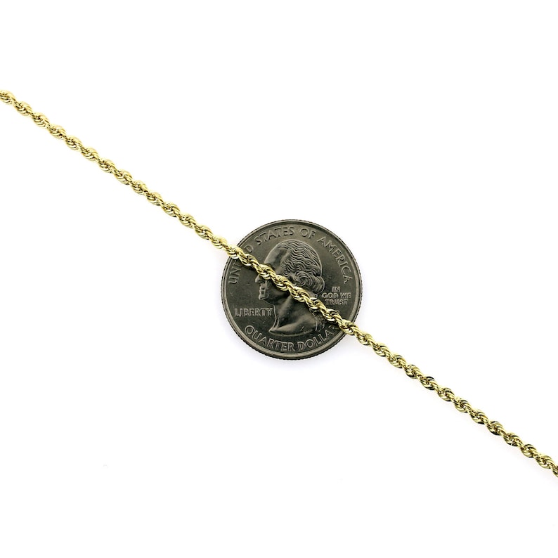 May include: A gold rope chain necklace, shown next to a US quarter for size comparison. The chain is made of a braided, twisted design.
