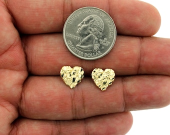 May include: A pair of gold heart-shaped earrings with a textured finish. The earrings are shown next to a US quarter for size comparison.