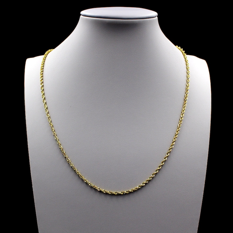 May include: A gold rope chain necklace on a white mannequin bust.