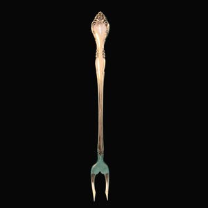 May include: A gold-colored, ornate fork with a decorative handle and two tines. The handle features a floral design and a pearlescent insert. The tines are a contrasting silver color. The fork is likely for serving or decorative purposes.