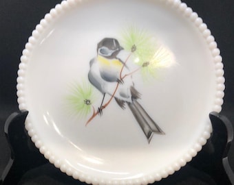 May include: A white milk glass oval dish with a beaded edge features a hand-painted design of a small bird perched on a branch with green pine needles.