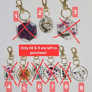 May include: A collection of keychains with gold-colored hardware. The keychains feature various dried flowers and butterflies encased in clear resin. The text "Only #2 & 9 are left to purchase!" is visible in a red rectangle.