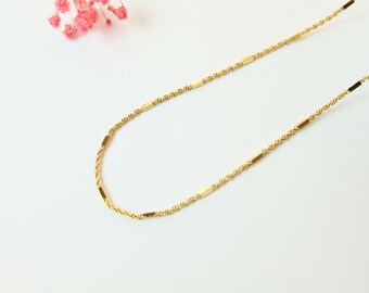 May include: A gold chain necklace with small rectangular accents.