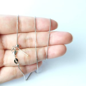 May include: A silver chain necklace with a lobster clasp and a small silver bead at the end.