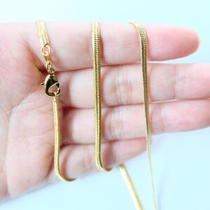 May include: A gold snake chain necklace with a lobster clasp closure.