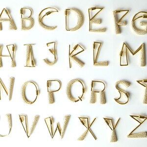 May include: Gold-toned alphabet letter charms with a clear crystal embellishment. Each letter is a separate charm.