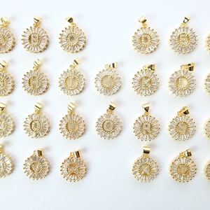 May include: A set of 26 gold-toned pendants, each featuring a different letter of the alphabet surrounded by clear cubic zirconia stones.