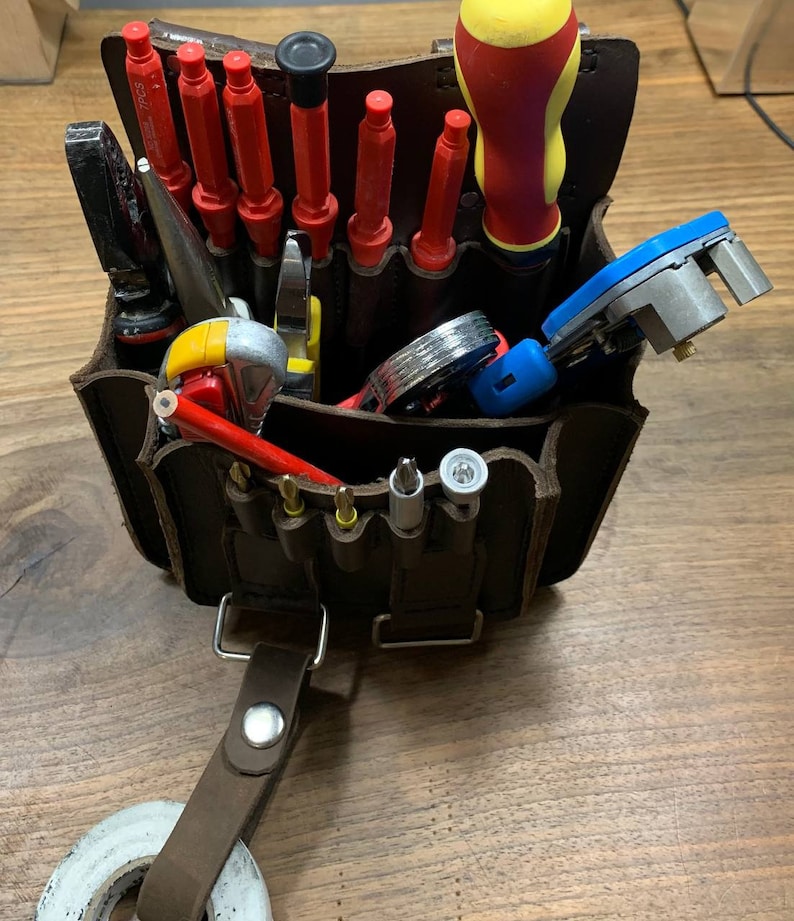 May include: A brown leather tool belt with a variety of tools, including screwdrivers, pliers, and a pencil. The belt has a loop for attaching to a belt.