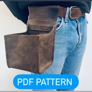 Puede incluir: Un cinturón de herramientas de cuero marrón con una bolsa cuadrada adjunta. El cinturón se lleva alrededor de la cintura de una persona que lleva pantalones vaqueros azules. El texto "PDF PATTERN" se muestra en una pancarta azul.