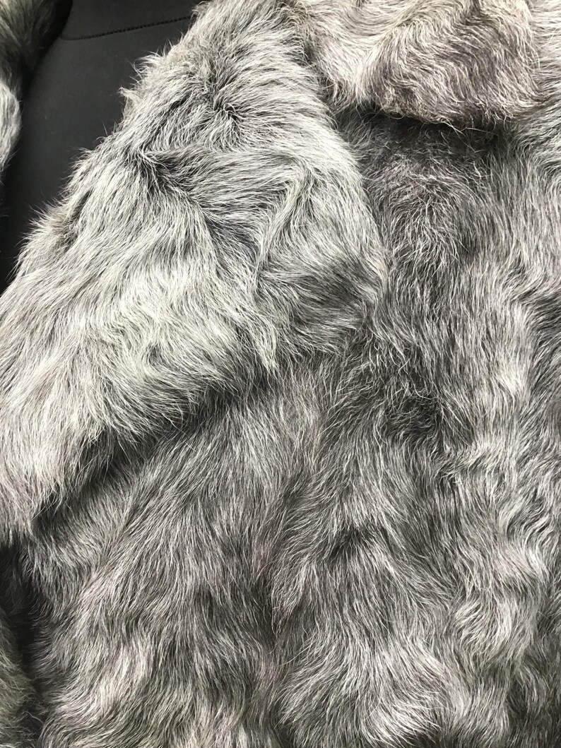 May include: Close-up of a gray faux fur fabric with a soft, fluffy texture.