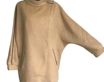 May include: A tan, long-sleeved,  oversize  coat with a high collar and black trim. The coat has a  diagonal zipper closure and two pockets.