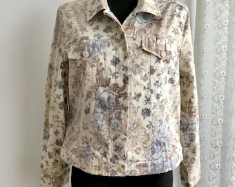 May include: A cream-coloured denim jacket with a floral print. The jacket has a button-up front, long sleeves, and two pockets on the chest.