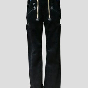 Könnte beinhalten: Schwarze Cordhose mit zwei goldenen Reißverschlüssen am Bund. Die Hose hat ein gerades Bein-Design und verfügt über kleine Taschen an den Seiten. Die Hose wird vor einem hellgrauen Hintergrund gezeigt.
