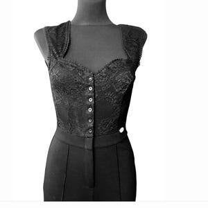 May include: A black lace bodice with a button-up front and a fitted silhouette. The bodice is part of a jumpsuit with black pants.