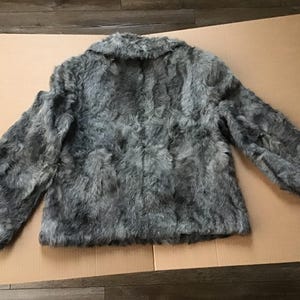 May include: A gray faux fur jacket with a collar and long sleeves.