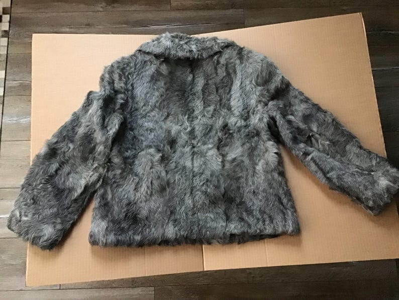 May include: A gray faux fur jacket with a collar and long sleeves.