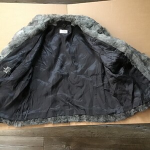May include: A gray faux fur jacket with a black lining. The jacket is unbuttoned and the lining is visible.