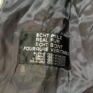 May include: A black fur coat label with the text "ECHT PELZ REAL FUR ECHT BONT FOURRURE VERITABLI" and the lining details: "FUTTER 100% VISKOSE LINING 100% VISCOSE VOERING 100% VISCOSE DOUBLURE 100% VISCOSE".