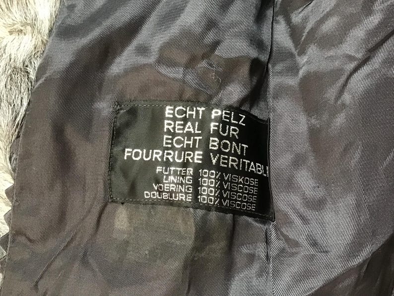 May include: A black fur coat label with the text "ECHT PELZ REAL FUR ECHT BONT FOURRURE VERITABLI" and the lining details: "FUTTER 100% VISKOSE LINING 100% VISCOSE VOERING 100% VISCOSE DOUBLURE 100% VISCOSE".