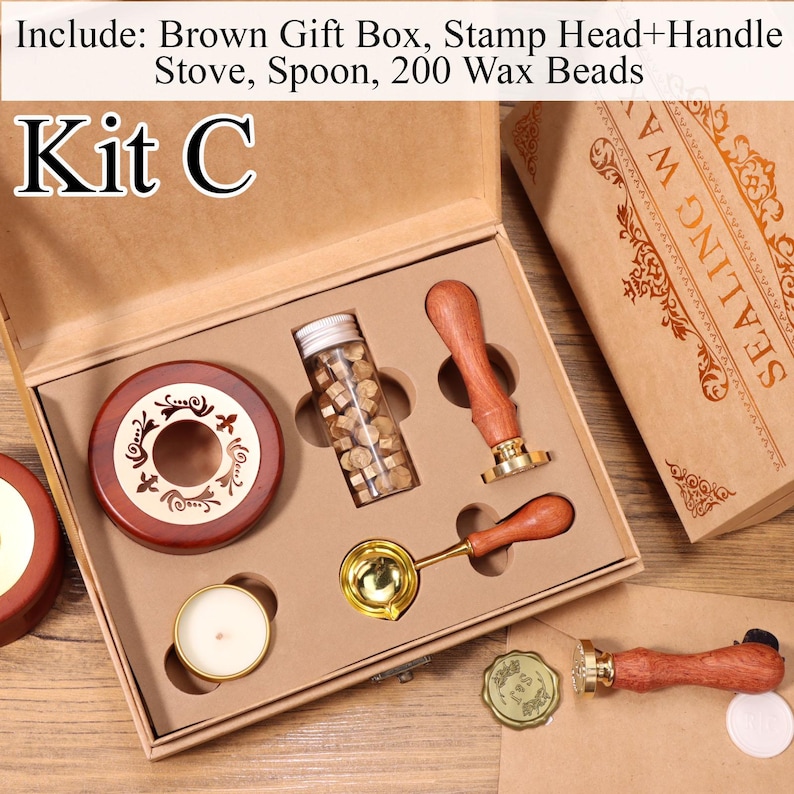 K&ouml;nnte beinhalten: Ein Wachssiegel-Set mit der Aufschrift Kit C in einer braunen Geschenkbox, bestehend aus einem Holzofen, einem Schmelzl&ouml;ffel aus Metall, einem Glasfl&auml;schchen mit 200 Wachsperlen und zwei Stempeln mit Holzgriff. Enth&auml;lt ein wei&szlig;es Teelicht.