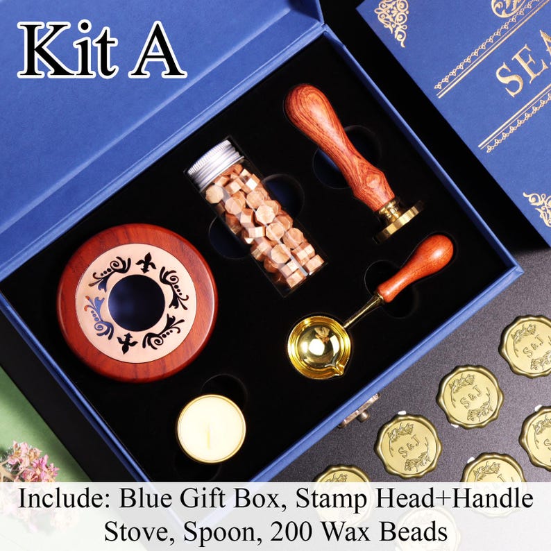 K&ouml;nnte beinhalten: Eine blaue Geschenkbox mit einem Wachssiegel-Set, beschriftet als Kit A. Das Set enth&auml;lt einen Stempel mit Holzgriff, einen Schmelzl&ouml;ffel aus Metall, einen Holzofen, ein Teelicht, ein Glasr&ouml;hrchen mit 200 Wachsperlen und fertige Wachssiegel.