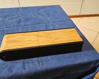 May include: A wooden box with a black trim and a hinged lid. The box is made of light wood with a natural grain.