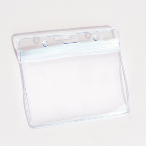 Pode incluir: Porta-crachá de plástico transparente com uma fenda horizontal para inserir um crachá ou cartão de identificação. O porta-crachá tem dois furos na parte superior para prender um cordão ou um clipe.