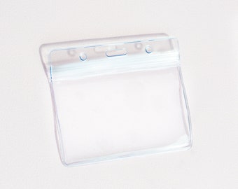 Puede incluir: Porta credenciales de plástico transparente con una ranura horizontal para insertar una credencial o tarjeta de identificación. El porta credenciales tiene dos agujeros en la parte superior para sujetar un cordón o un clip.
