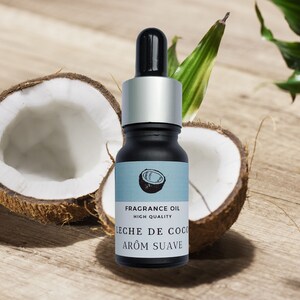 May include: A small glass bottle of coconut fragrance oil with a silver cap and dropper. The bottle is labeled "FRAGRANCE OIL HIGH QUALITY LECHE DE COCO AROM SUAVE". The bottle is sitting on a wooden surface with two halves of a coconut.