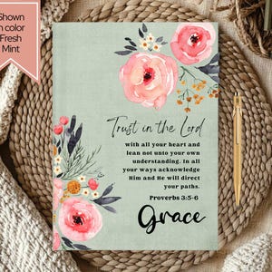 May include: A Fresh Mint-colored journal with floral watercolor illustrations and the text "Trust in the Lord." The journal features pink roses and other flowers. A gold pen rests beside the journal.