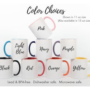 May include: A collection of white ceramic mugs with colored rims and handles, showcasing various color options: pink, light blue, navy, purple, black, red, orange, and yellow. Each mug has a corresponding color name written on it. The mugs are available in 11 oz and 15 oz sizes.
