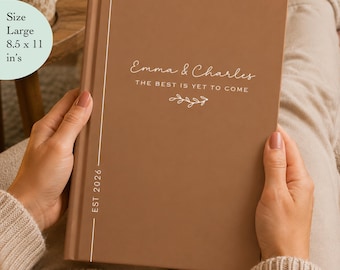 May include: A large 8.5 x 11 inch brown hardcover book with white text reading Emma & Charles, The Best Is Yet To Come, and Est 2026. The cover features a simple white line design along the spine and a small decorative leaf graphic.