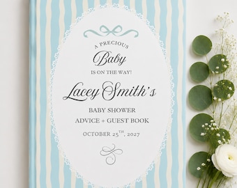 May include: A hardcover baby shower advice and guest book with a light blue and white vertical wavy striped cover. The center features a white oval frame with a lace border, containing the text A PRECIOUS Baby IS ON THE WAY! Lacey Smith's BABY SHOWER ADVICE + GUEST BOOK OCTOBER 25TH, 2027.