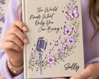 May include: A beige hardcover journal featuring a silver vintage microphone, purple butterflies, and floral vines. The text reads, "The World Needs What Only You Can Bring" and the name "Sally" is printed in black script at the bottom right corner.