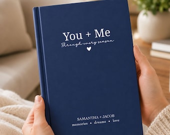 May include: A navy blue hardcover journal featuring white text that reads You + Me Through every season with a small heart icon. The bottom of the cover includes the names SAMANTHA + JACOB followed by the words memories, dreams, and love.