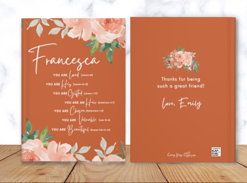 May include: A burnt orange book cover featuring watercolour floral illustrations in peach and green. The front displays the name Francesca and a list of affirmations with scripture references. The back reads Thanks for being such a great friend! Love, Emily.