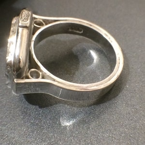 May include: A silver ring with a detailed design and the number "925" engraved on the side.