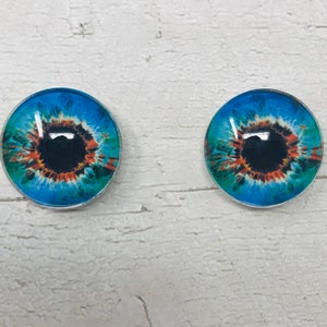 May include: Two blue glass eyes with brown and green accents. The eyes are round and have a black pupil.