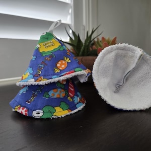 May include: Two cone-shaped fabric covers with a blue base featuring a colorful cartoon print of candies and the text Lucky Boy. The exterior is blue cotton with a white terry cloth lining and a small white fabric loop at the top of one cone.